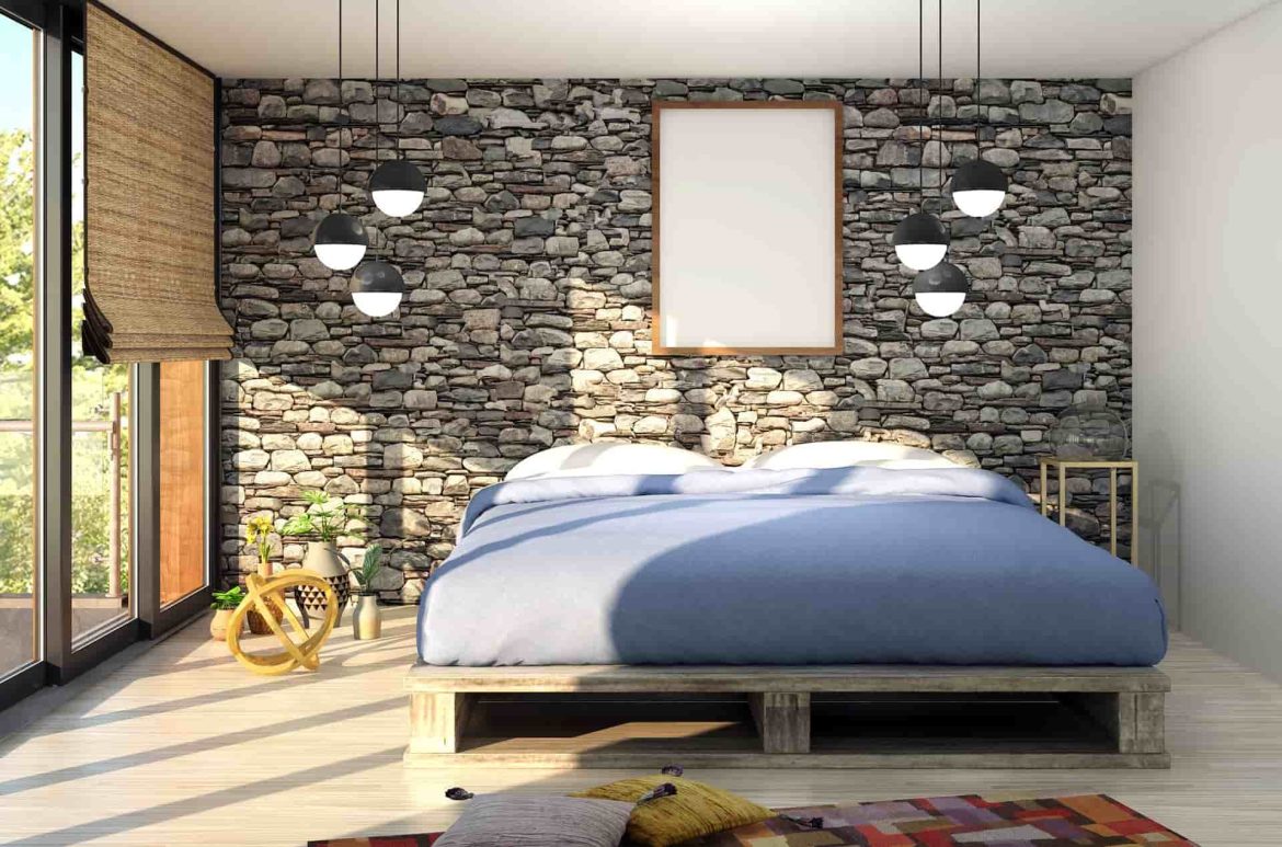 Un lit escamotable en bois installé dans une chambre moderne avec un mur en pierre, de grandes baies vitrées et des luminaires suspendus.