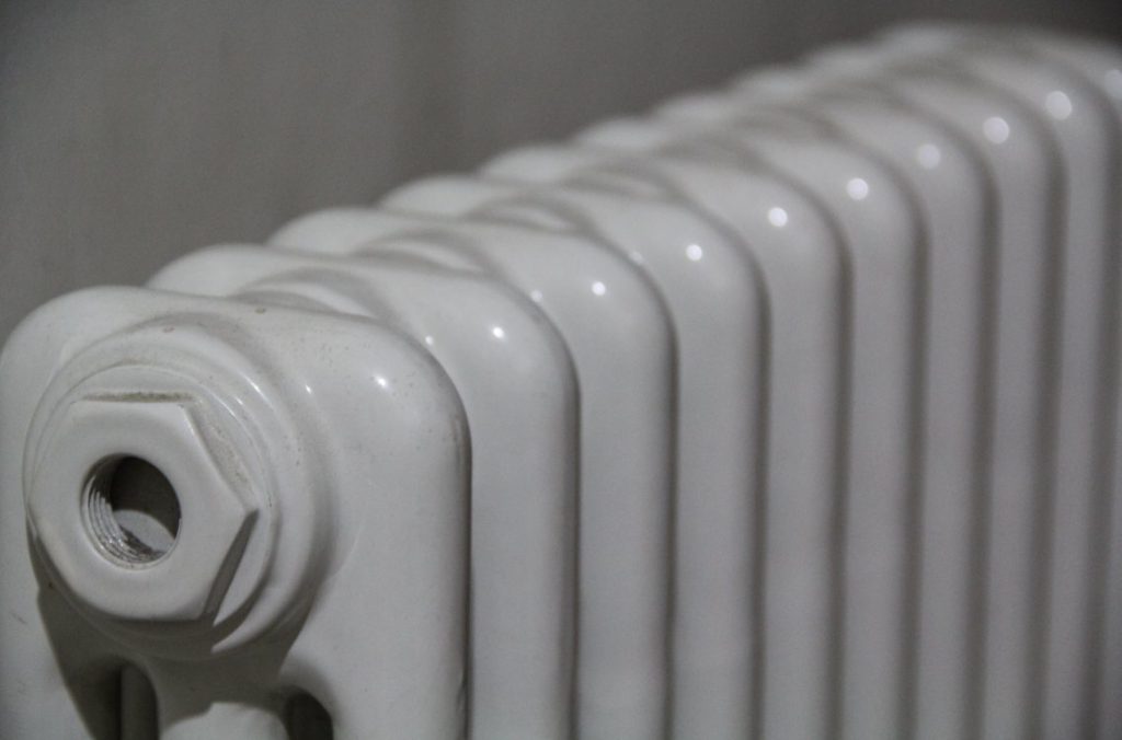 Gros plan sur le robinet et le bouchon de purge d'un radiateur ancien en fonte, indispensable pour purger vieux réseau chauffage central.
