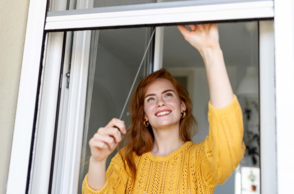 Une femme heureuse ouvre une fenêtre moderne. Si vous avez besoin d'un changement de serrure suite perte de clef serrurier Paris, contactez un professionnel.