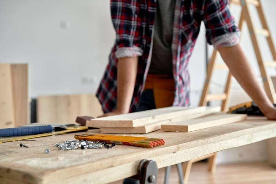Un artisan en chemise à carreaux travaille sur un établi de menuisier en bois massif